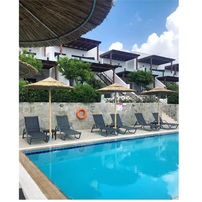a pool with chairs and umbrellas next to a building at Southern Dreams Apartments in Gennadi