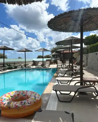 a swimming pool with chairs and umbrellas and a donut in the water at Southern Dreams Apartments in Gennadi