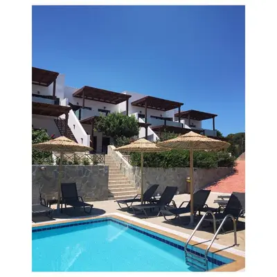 a swimming pool with chairs and umbrellas next to a building at Southern Dreams Apartments in Gennadi