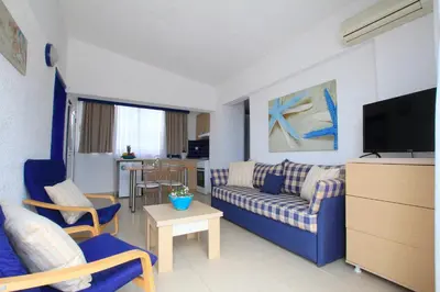 a living room with a blue couch and a tv at Christiana Hotel Apartments in Gennadi