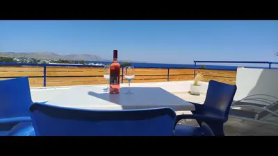 a bottle of wine sitting on a table with chairs at Christiana Hotel Apartments in Gennadi