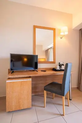 a room with a desk with a television and a chair at D'Andrea Mare Hotel in Ialyssos