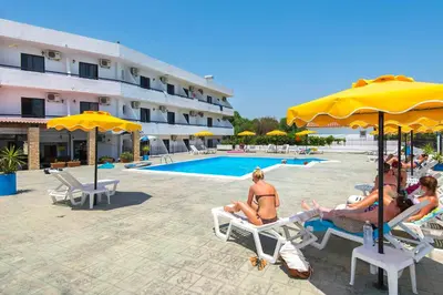 a group of people sitting on lawn chairs by a pool at Butterfly Studios, Faliraki in Faliraki