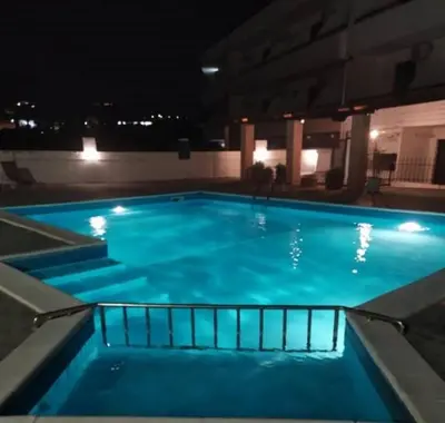 a large blue swimming pool at night at Butterfly Studios, Faliraki in Faliraki