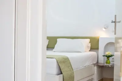 a bedroom with a bed with white sheets and a table at Sabrina Studios in Faliraki