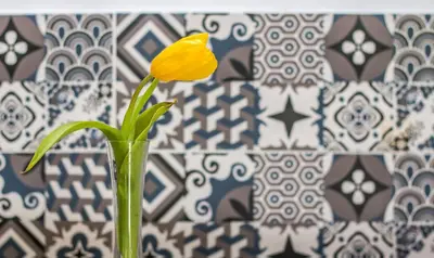 a yellow flower in a vase in front of a wall at Sabrina Studios in Faliraki