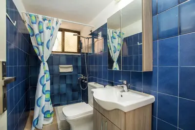 a blue tiled bathroom with a sink and a toilet at Sabrina Studios in Faliraki