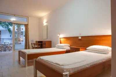 a hotel room with two beds and a balcony at Coliseum Studios & Apartments in Pefki Rhodes