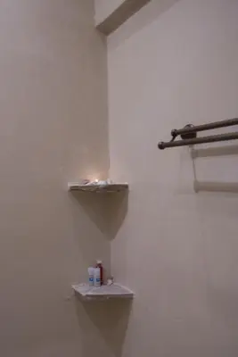 a bathroom with a white wall with two shelves at Kathara Bay Apartments in Faliraki