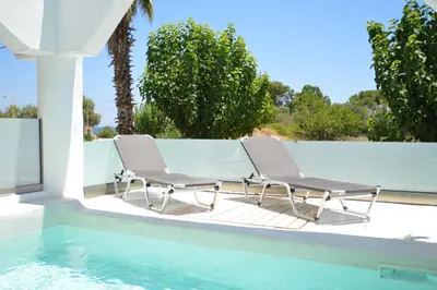 two chairs sitting on a patio next to a swimming pool at Kathara Bay Apartments in Faliraki
