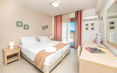 a bedroom with a bed and a desk and a window at Blue Wave Villa in Gennadi