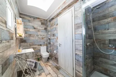 a bathroom with wooden walls and a toilet and a shower at Anelia Boutique Studios & Apartments in Faliraki