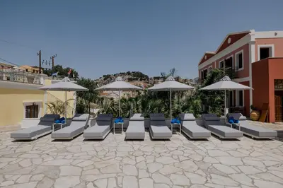 a group of lounge chairs and umbrellas on a patio at Opera House Hotel in Symi