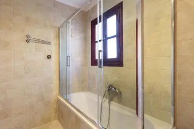a bathroom with a tub and a shower with a glass door at Opera House Hotel in Symi