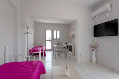 a living room with a pink bed and a kitchen at Rhodes Paulsia Cosy Apartments in Psinthos