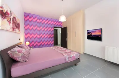 a bedroom with a purple bed with a pink headboard at Filerimos Garden Villa in Ialyssos