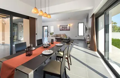 a dining room and living room with a table and chairs at Filerimos Garden Villa in Ialyssos