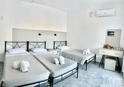 a bedroom with two beds and a desk at Kedros Rooms in Prasonisi