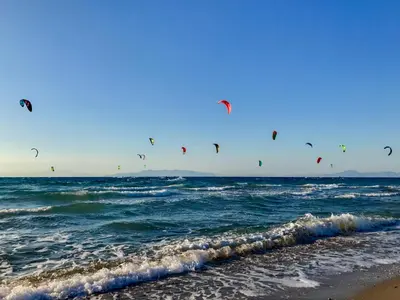 a group of people flying kites over the ocean at Villa Acacia in Phanaes