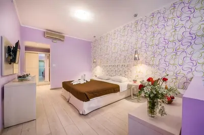 a bedroom with a bed and a purple wall at Filerimos Village Hotel in Ialyssos