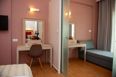 a room with a bed and a desk and mirror at Filerimos Village Hotel in Ialyssos