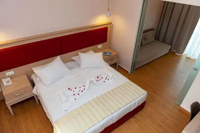 a bedroom with a large white bed with red accents at Filerimos Village Hotel in Ialyssos
