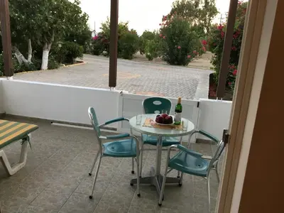a table and chairs on a patio with a bottle of wine at VILLA EIRINI in Pefki Rhodes