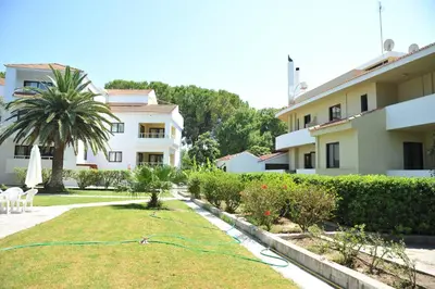 a garden in front of a building with a hose at Niki Hotel Apartments in Ialyssos