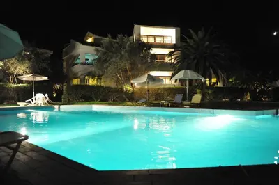 a large swimming pool at night with a building in the background at Niki Hotel Apartments in Ialyssos