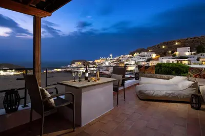 a patio with a view of the city at night at Villa Valasia Lindos with Acropolis View in Líndos