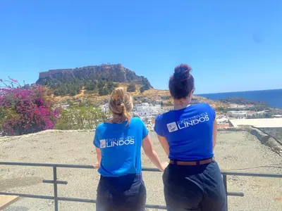 two people standing on a ledge looking at the ocean at Villa Valasia Lindos with Acropolis View in Líndos