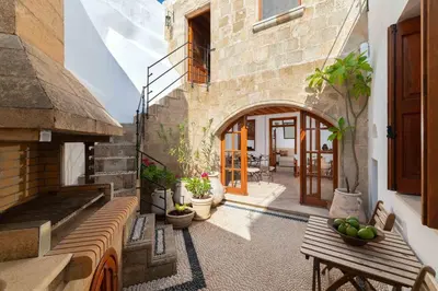an outdoor patio with a wooden bench and a building at Villa Valasia Lindos with Acropolis View in Líndos