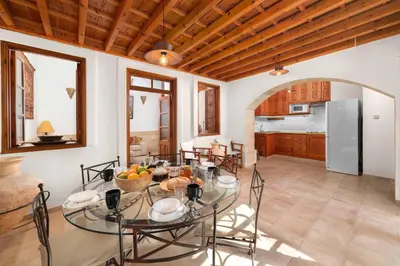 a kitchen and dining room with a glass table at Villa Valasia Lindos with Acropolis View in Líndos