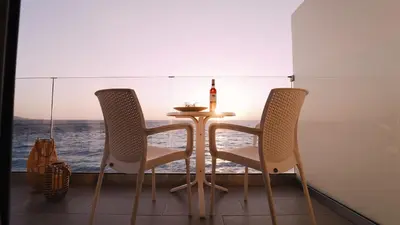 a table and two chairs on a balcony with the ocean at Sunrise Luxury Apartments Rhodes in Rhodes Town