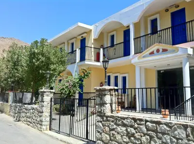 a house with a fence and a stone wall at Castellania Hotel Apartments in Livadia