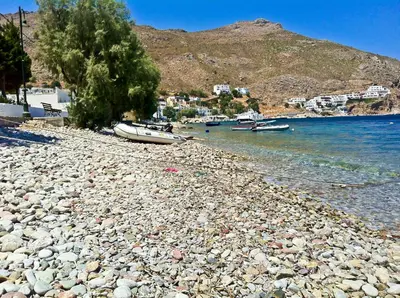 a rocky beach with boats on the water at Castellania Hotel Apartments in Livadia