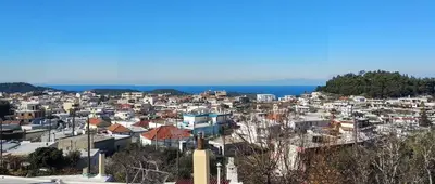 a city with houses and the ocean in the background at Rustic House in Émbonas