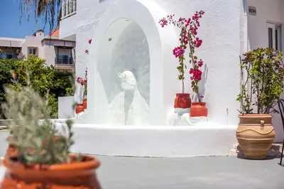 a statue in a white building with flowers in pots at Tinas Plus Hotel in Faliraki