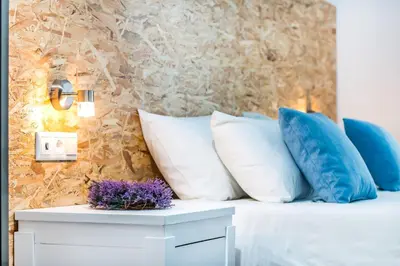 a bed with white pillows and purple flowers on it at Tinas Plus Hotel in Faliraki