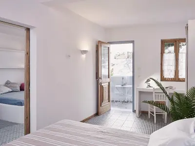a white bedroom with a bed and a bathroom at Kalithea Hills Appartment 1 in Koskinou