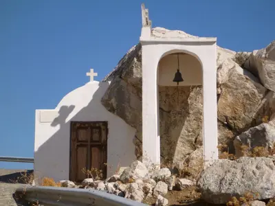 a small white chapel with a cross on a pile of rocks at Bright Sun Villas in Halki