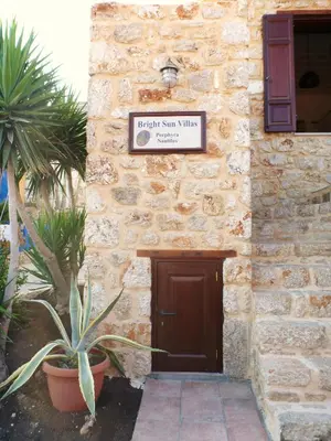 a sign on the side of a stone building with a door at Bright Sun Villas in Halki
