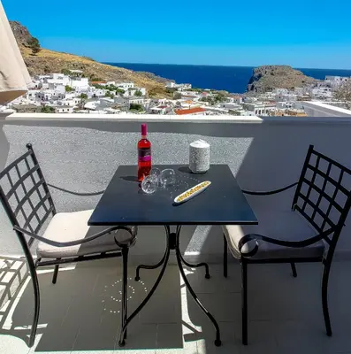 a table with a bottle and two chairs on a balcony at Domna Studios in Líndos