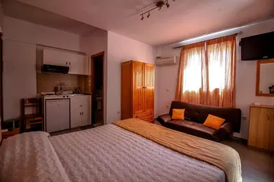 a bedroom with a bed and a couch and a kitchen at Domna Studios in Líndos