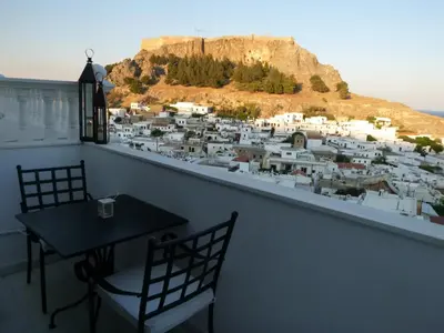a balcony with a table and chairs and a city at Domna Studios in Líndos