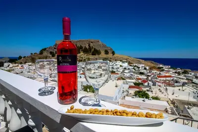 a bottle of wine sitting on a table with wine glasses at Domna Studios in Líndos