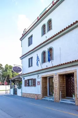 a white building with two flags on top of it at Takis Hotel Apartments in Ialyssos