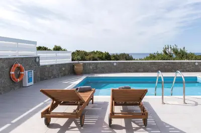 two chairs sitting next to a swimming pool at Villa Sea La Vie in Kiotari