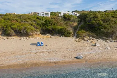 two blue chairs and an umbrella on a beach at Villa Sea La Vie in Kiotari