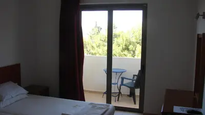 a room with a bed and a window with a table at Apostolis studios Pefki Lindos Rhodes in Pefki Rhodes